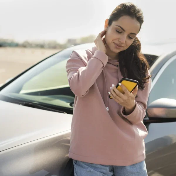 Mulher encostada no carro solicitando assistência 24 horas após uma pane elétrica no carro.