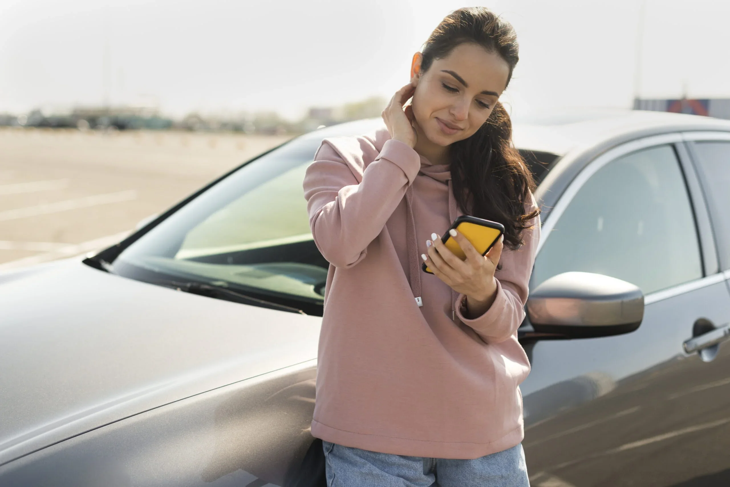 Mulher encostada no carro solicitando assistência 24 horas após uma pane elétrica no carro.